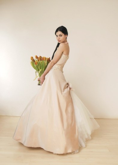 Ein modell im Brautkleid mit einm Tulpenstrauß in den Händen